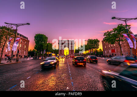 Paris, France - July 2, 2017: Avenue des Champs Elysees and iconic Arc de Triomphe at twilight with traffic street. Arch of Triumph in a colorful sunset sky. Stock Photo