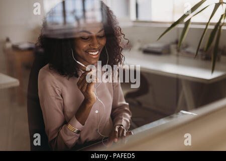 Businesswoman working on laptop computer and talking using earphones sitting at home. Businesswoman managing business from home working on laptop. Stock Photo