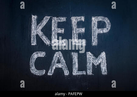 Text Keep calm written in chalk on a black board. Stock Photo