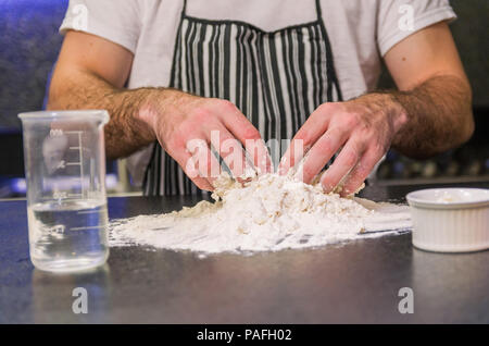 Man preparing pizza dough on black granite table Stock Photo