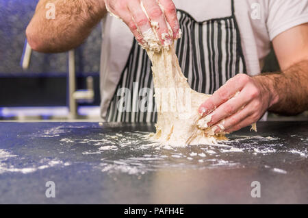 Man preparing pizza dough on black granite table Stock Photo