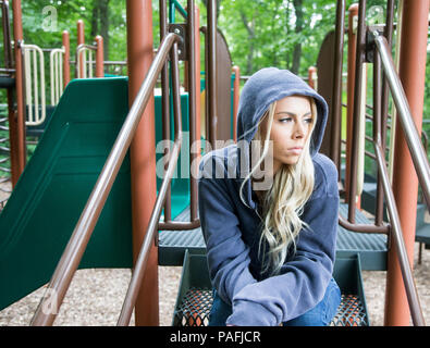 Teenage girl sitting at a playground in a sullen mood Stock Photo