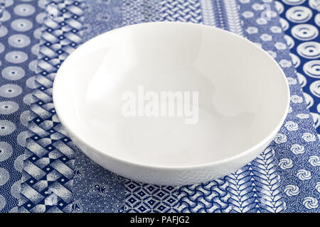 Bowl - Empty white dish on blue and white indigo table cloth background close up Stock Photo