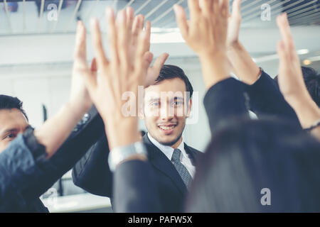Happy Business people showing team work and giving five after signing agreement or contract with foreign partners in office interior. Stock Photo
