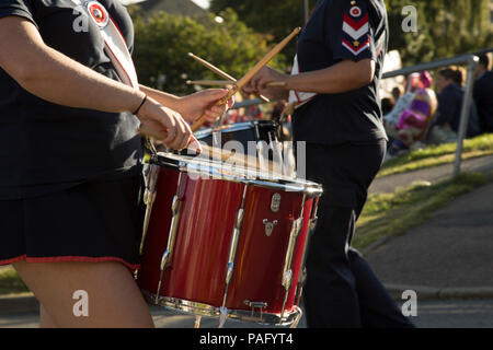 Woman in a black and red uniform in a parade or playing the drum with motion in the drumstick.  red shiny drum with silver details. Stock Photo