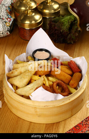 Mixed appetizer of french fries, fried sasusage, fried zucchini, pastry, sigara borek with sauces Stock Photo