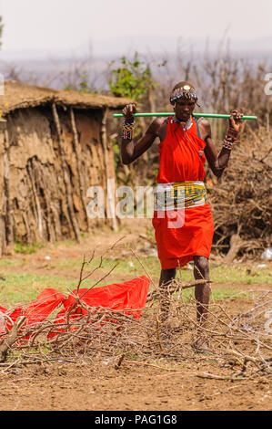 AMBOSELI, KENYA - OCTOBER 10, 2009: Unidentified Massai woman walks wearing typical tribal red clothes and carring   a rocker for water in Kenya, Oct  Stock Photo