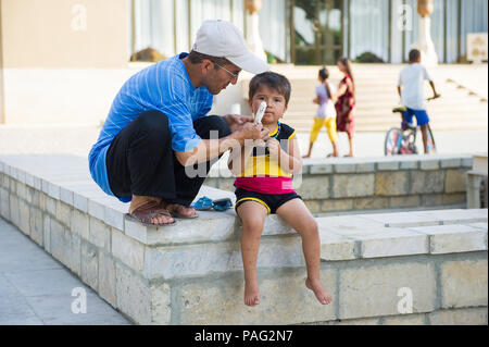 BUKHARA, UZBEKISTAN - JUNE 6, 2011: Unidentified Uzbek man gives an ice cream to his child in Uzbekistan, Jun 6, 2011.  81% of people in Uzbekistan be Stock Photo