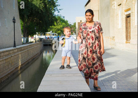 BUKHARA, UZBEKISTAN - JUNE 6, 2011: Unidentified Uzbek woman goes for a walk with her child Uzbekistan, Jun 6, 2011.  81% of people in Uzbekistan belo Stock Photo