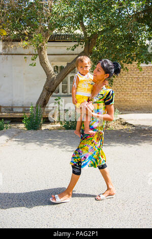 BUKHARA, UZBEKISTAN - JUNE 7, 2011: Unidentified Uzbek woman goes for a walk with her child Uzbekistan, Jun 7, 2011.  81% of people in Uzbekistan belo Stock Photo