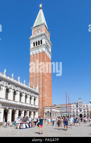 Campanile or bell tower of St Marks Cathedral, Piazza San Marco, San Marco, Venice, Veneto, Italy with tourists against a blue sky Stock Photo