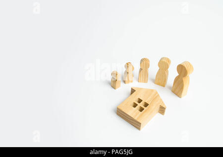 Wooden figures of people from small to large stand around the house. The concept of home purchase, family planning and extension of living space. Rent Stock Photo