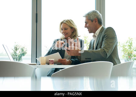 Businesspeople using laptop and smart phone in cafeteria Stock Photo