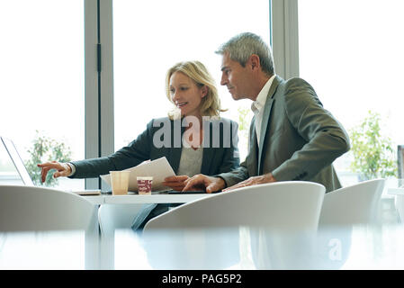 Businesspeople using laptop in cafeteria Stock Photo