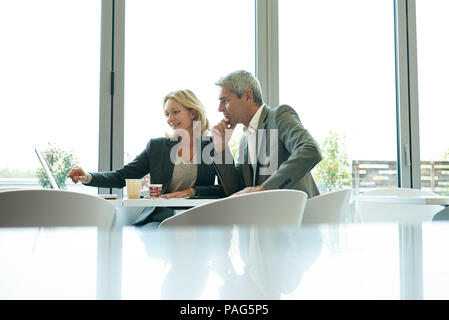 Businesspeople using laptop in cafeteria Stock Photo
