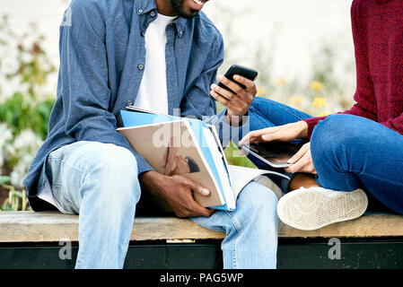 Students sitting together and using smart phone Stock Photo