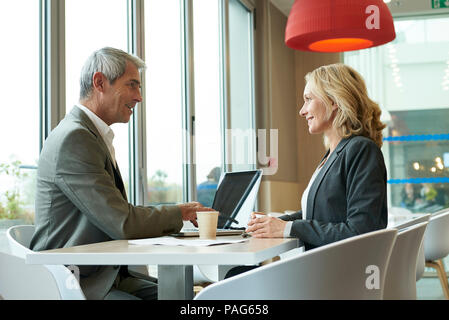 Businesspeople using laptop in cafeteria Stock Photo