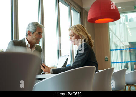 Businesspeople using smart phone in cafeteria Stock Photo
