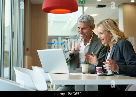 Businesspeople using laptop in cafeteria Stock Photo