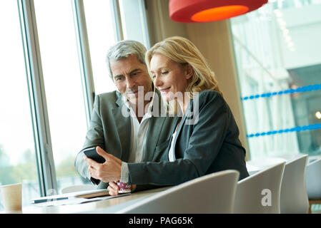 Businesspeople using smart phone in cafeteria Stock Photo