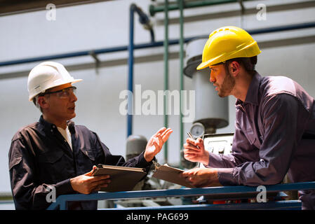 Factory workers discussing with each other in factory Stock Photo