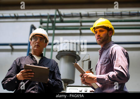 Factory workers with digital tablet and clipboard in factory Stock Photo