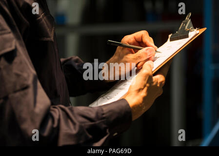 Factory worker writing on clipboard Stock Photo
