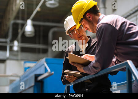Factory workers discussing with each other in factory Stock Photo