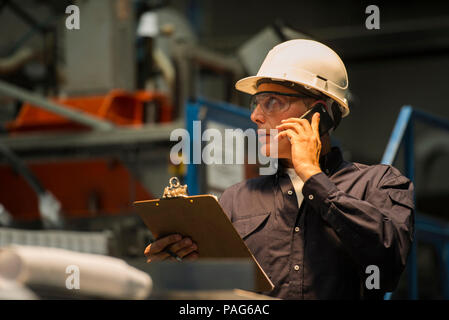 Factory worker using mobile phone in factory Stock Photo
