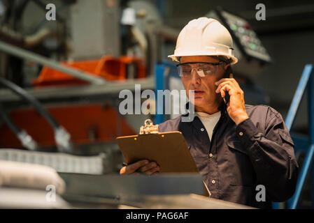 Factory worker using mobile phone in factory Stock Photo