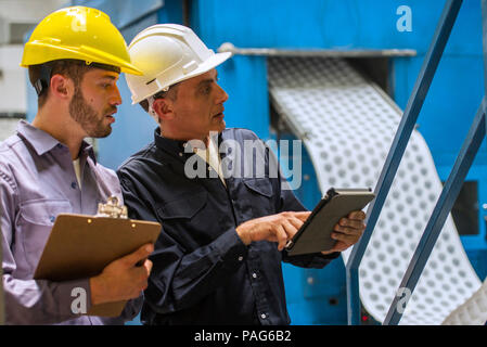 Factory workers discussing with each other in factory Stock Photo
