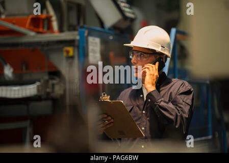 Factory worker using mobile phone in factory Stock Photo
