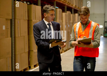 Worker and businessman with digital tablet and clipboard in warehouse Stock Photo