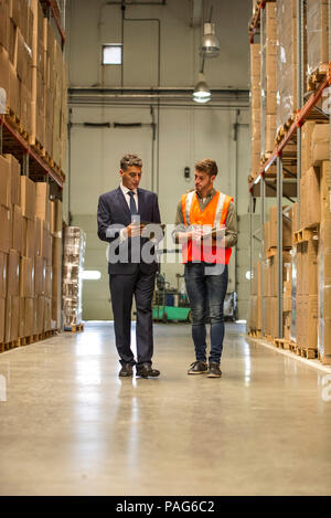 Worker and businessman with digital tablet and clipboard in warehouse Stock Photo