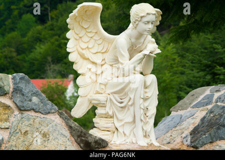Marble sculpture of female angel sitting on the rock and holding a bird in her hands, Albania, Europe Stock Photo