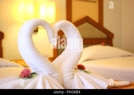 blurry photo of swans shaped of white towel on the bed Stock Photo