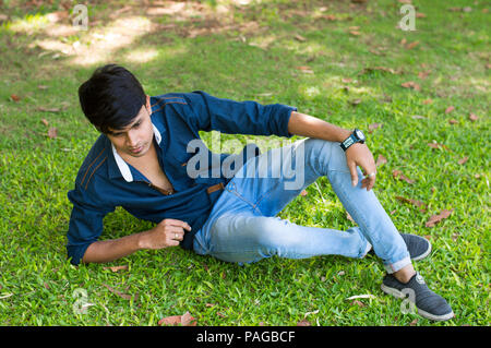 Young casual man laying on grass and thinking Stock Photo