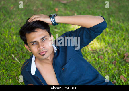 Closeup of a young man laying on grass and passing his hand through his hair Stock Photo