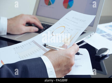 Business man check data from notebook and watch budget report on working table. Stock Photo