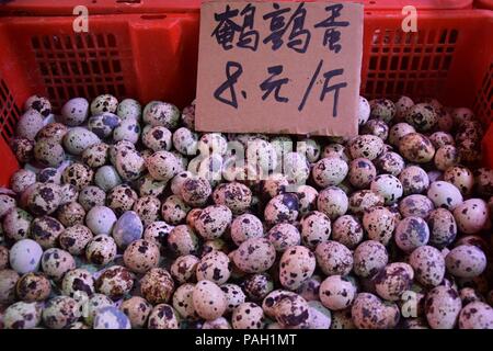 Fresh speckled quail eggs heaped up inside the  plastic basket. Translation: "quail eggs 8 yuan/half a kilo". Stock Photo