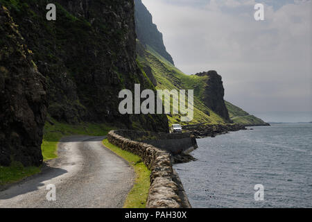 Van passing steep cliffs and rock wall of narrow Highway B8035 on the shore of Loch Na Keal on the Isle of Mull Scotland UK Stock Photo