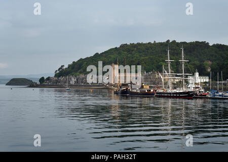 Sailing ships moored in Oban Harbour with St Columba's Cathedral on Oban Bay in the morning Scotland UK Stock Photo