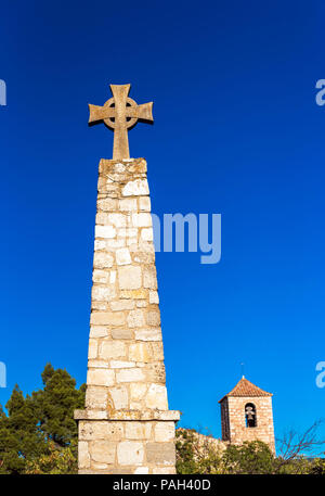Memorial Cross and Church of Santa Maria de Siurana in Siurana de Prades, Tarragona, Spain. Copy space for text. Vertical Stock Photo