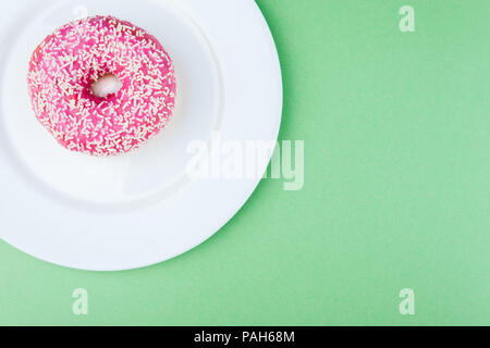 Pink glazed donut on green pastel background Stock Photo