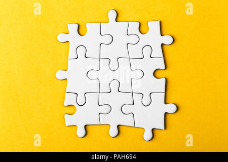 White details of puzzle on yellow background. Stock Photo