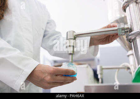 Technician filling container with liquid for laboratory tests Stock Photo