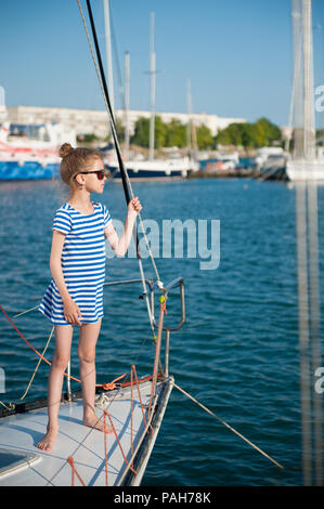 beautiful little girl in striped shirt and sunglasses on luxury yacht board Stock Photo