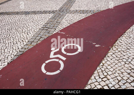 Traditional paving of the portuguese pavements and squares. Pattern created by combination of light and dark cobblestones. Red road for bicycles. Port Stock Photo