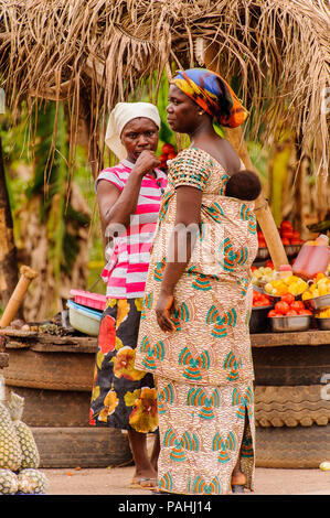 ACCRA, GHANA - MARCH 2, 2012: Unidentified Ghanaian woman with her child on her back at the market in the street in Ghana. People of Ghana suffer of p Stock Photo