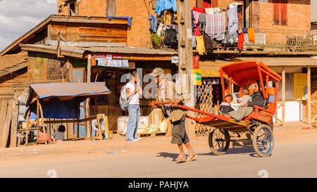 ANTANANARIVO, MADAGASCAR - JUNE 29, 2011: Unidentified Madagascar man carries  a transporting carriage with mother and children. People in Madagascar  Stock Photo